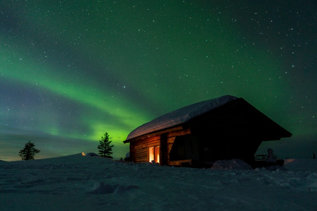 Houten hut onder het noorderlicht in een besneeuwd landschap