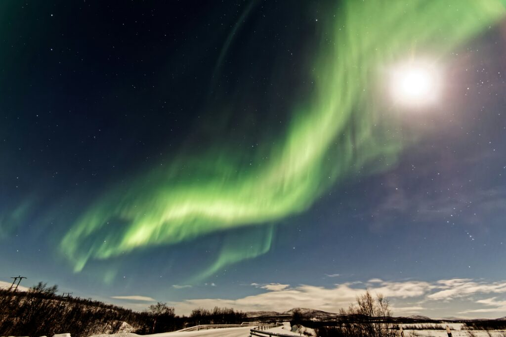 Noorderlicht en de maan boven een winterlandschap