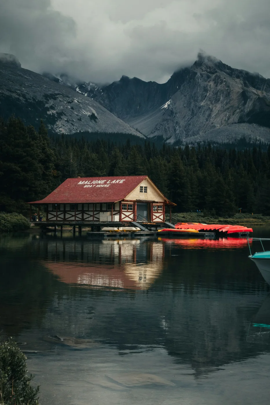 Botenhuis met rode kano’s aan Maligne Lake, met bos en bergen op de achtergrond