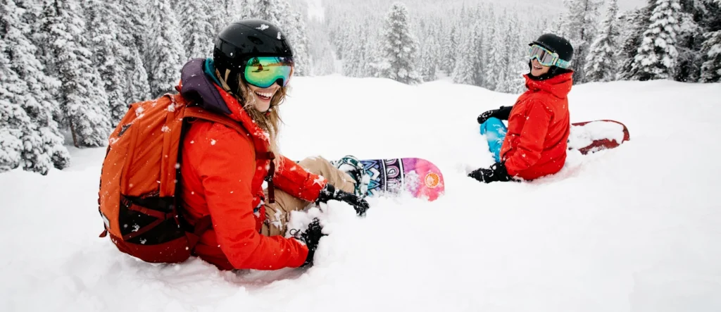 Twee snowboarders in de poedersneeuw tussen besneeuwde naaldbomen